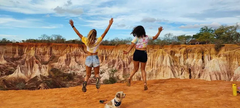 Two visitors jumping for joy in the red sandstone of Marafa canyon