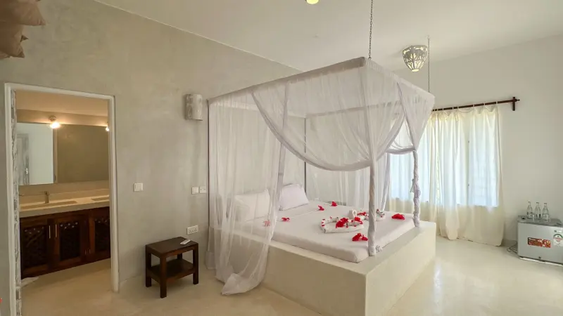 A bedroom with a four-poster bed and nets
