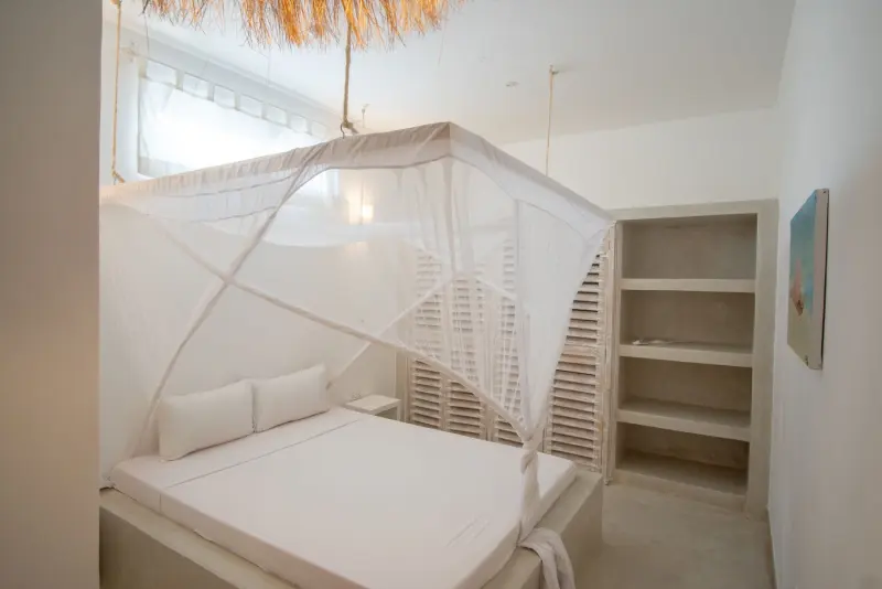 A bedroom with a net-draped bed and shelves