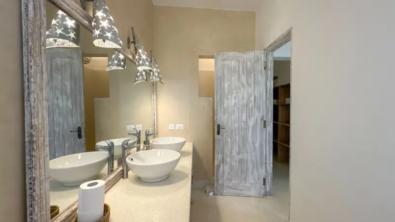 A bathroom with twin stone basins and carved doors