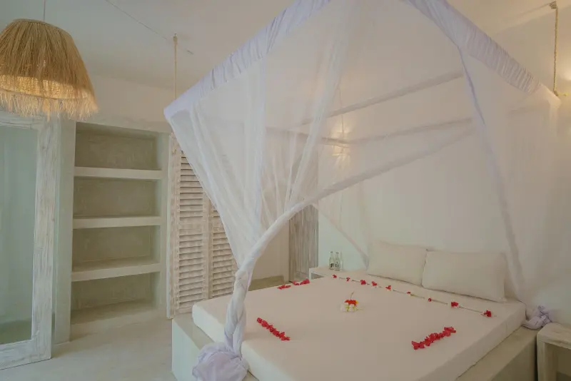 A net-draped double bed scattered with petals